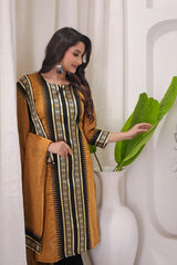 Woman wearing a mustard yellow and black patterned dress against a white curtain background