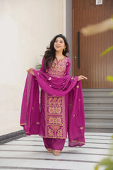 Woman in a vibrant pink traditional outfit with intricate patterns standing on a staircase.