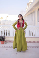 Woman in a green and red traditional outfit standing on a balcony with white railings and a clear sky.