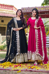 Two women in traditional outfits standing on a decorated ground with flowers.
