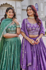 Two women in traditional green and purple dresses standing outdoors.