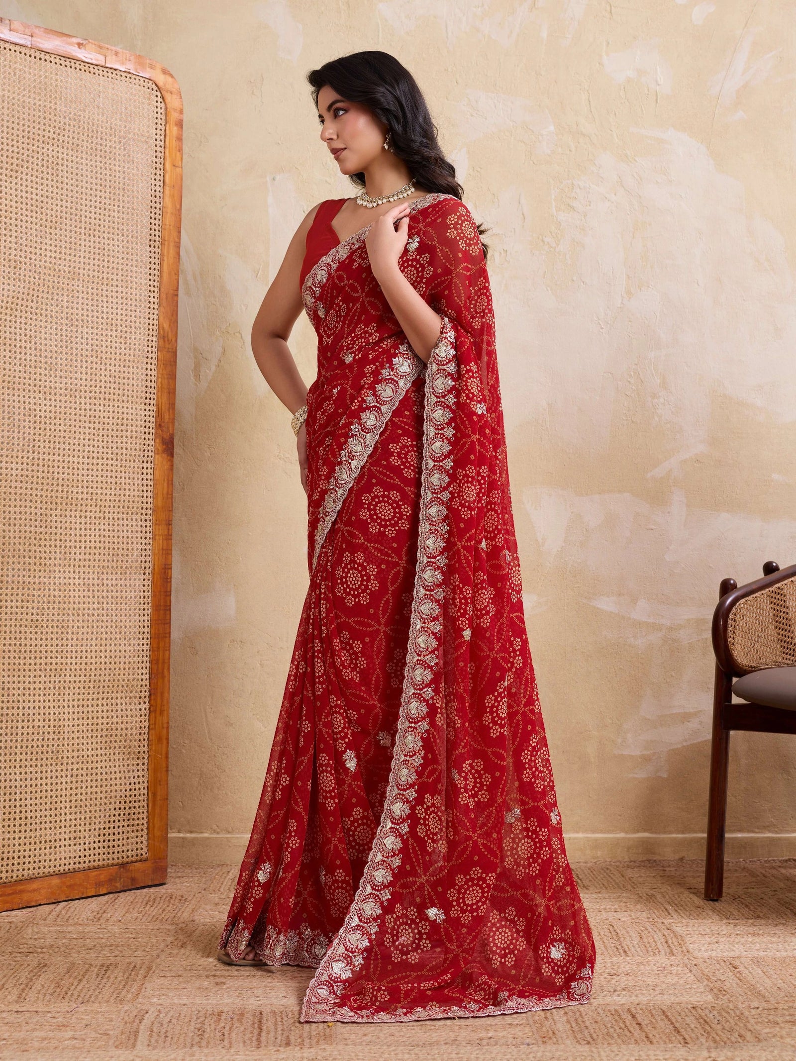 Woman wearing a red saree with white patterns in a room.