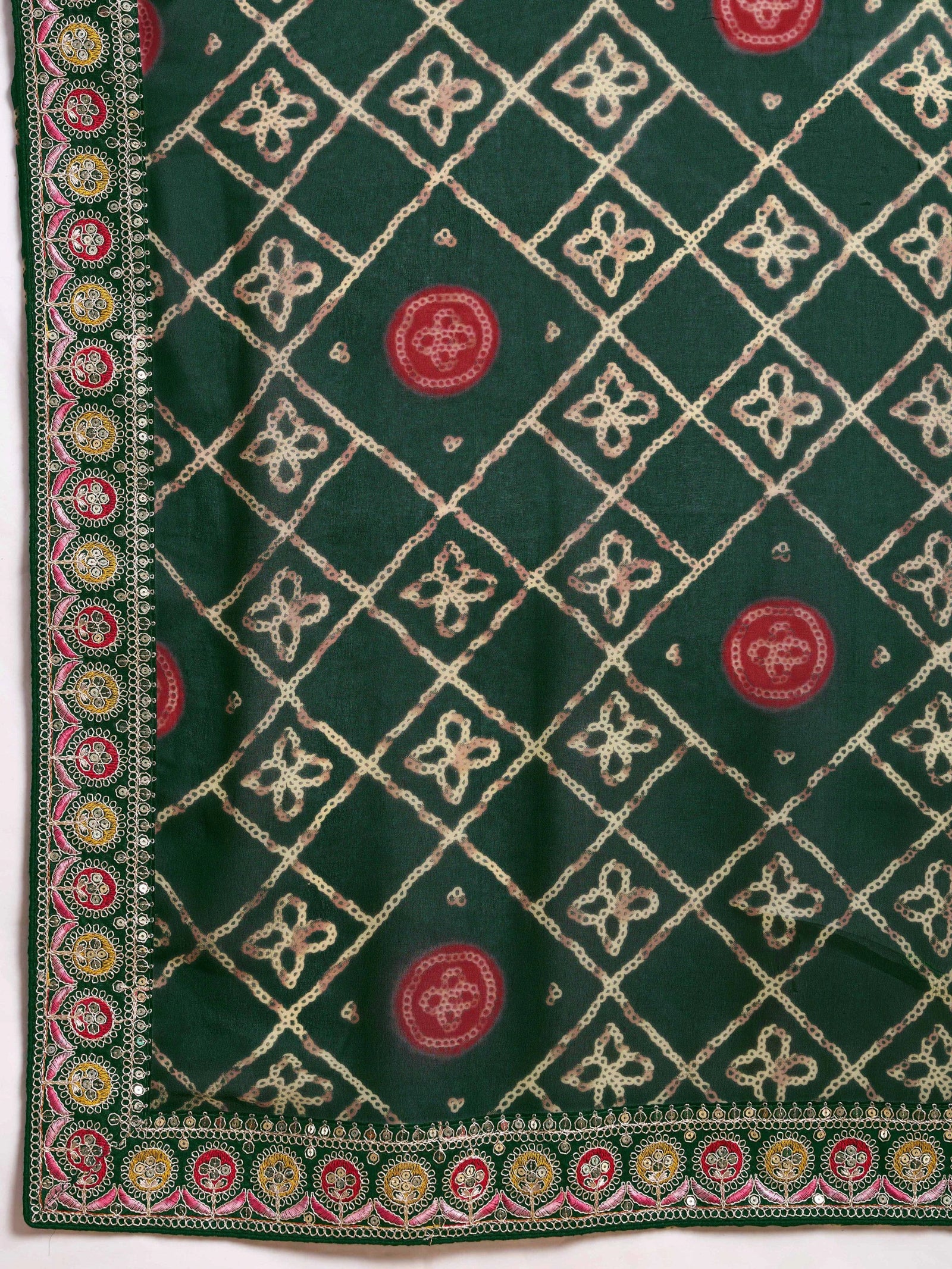 Green fabric with intricate white embroidery and red circular patterns on a white background