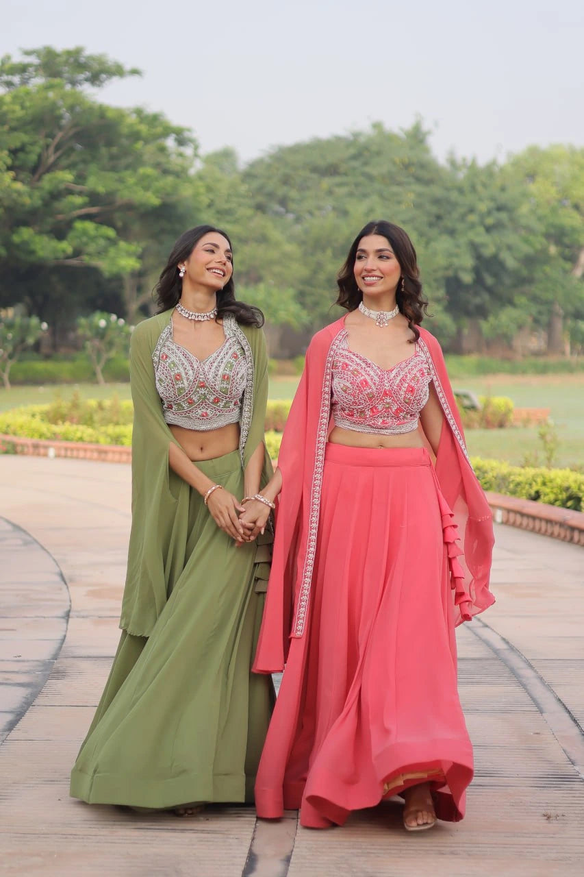 Two women in traditional outfits standing outdoors with greenery in the background