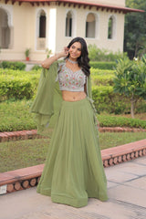 Woman in a green traditional outfit standing in a garden with a building in the background