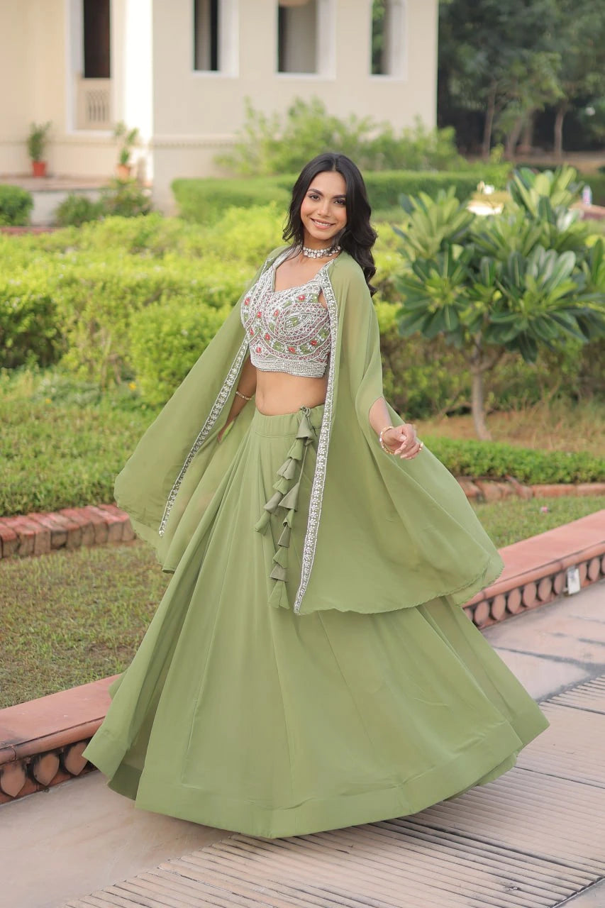 Woman in a green traditional outfit standing outdoors with greenery in the background