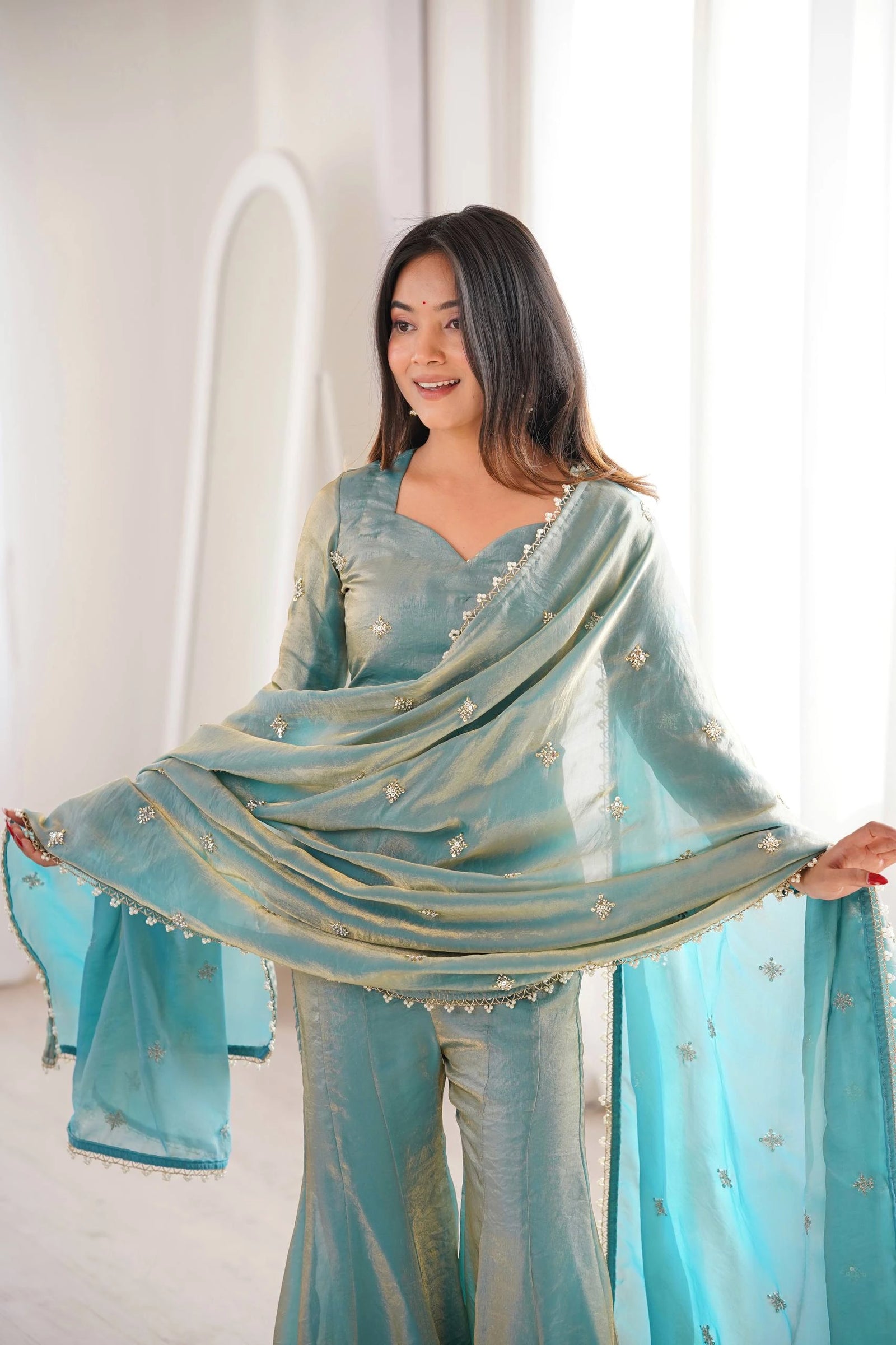 Woman wearing a light blue traditional outfit with a matching dupatta against a white background