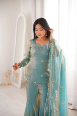 Woman in a light blue traditional outfit with a matching dupatta in a bright room.