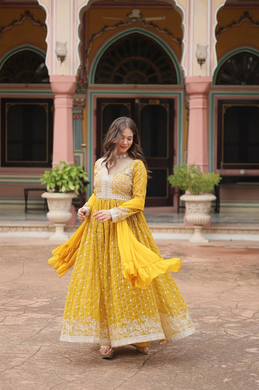 Woman in a yellow traditional outfit standing in front of an ornate building.