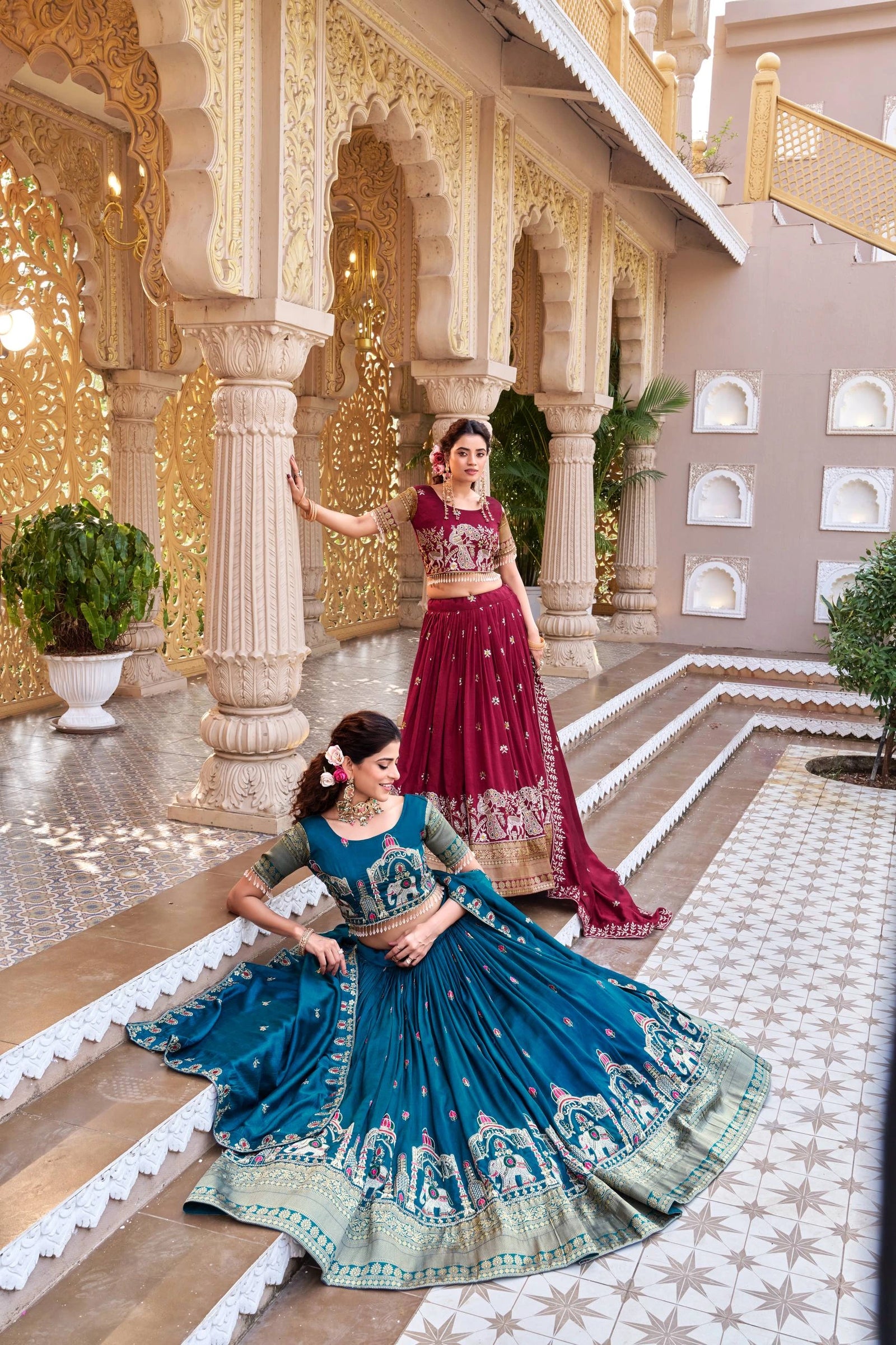Two women in traditional Indian attire standing in a decorative indoor setting.