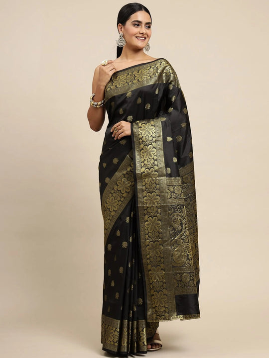Woman wearing a black saree with gold patterns on a beige background