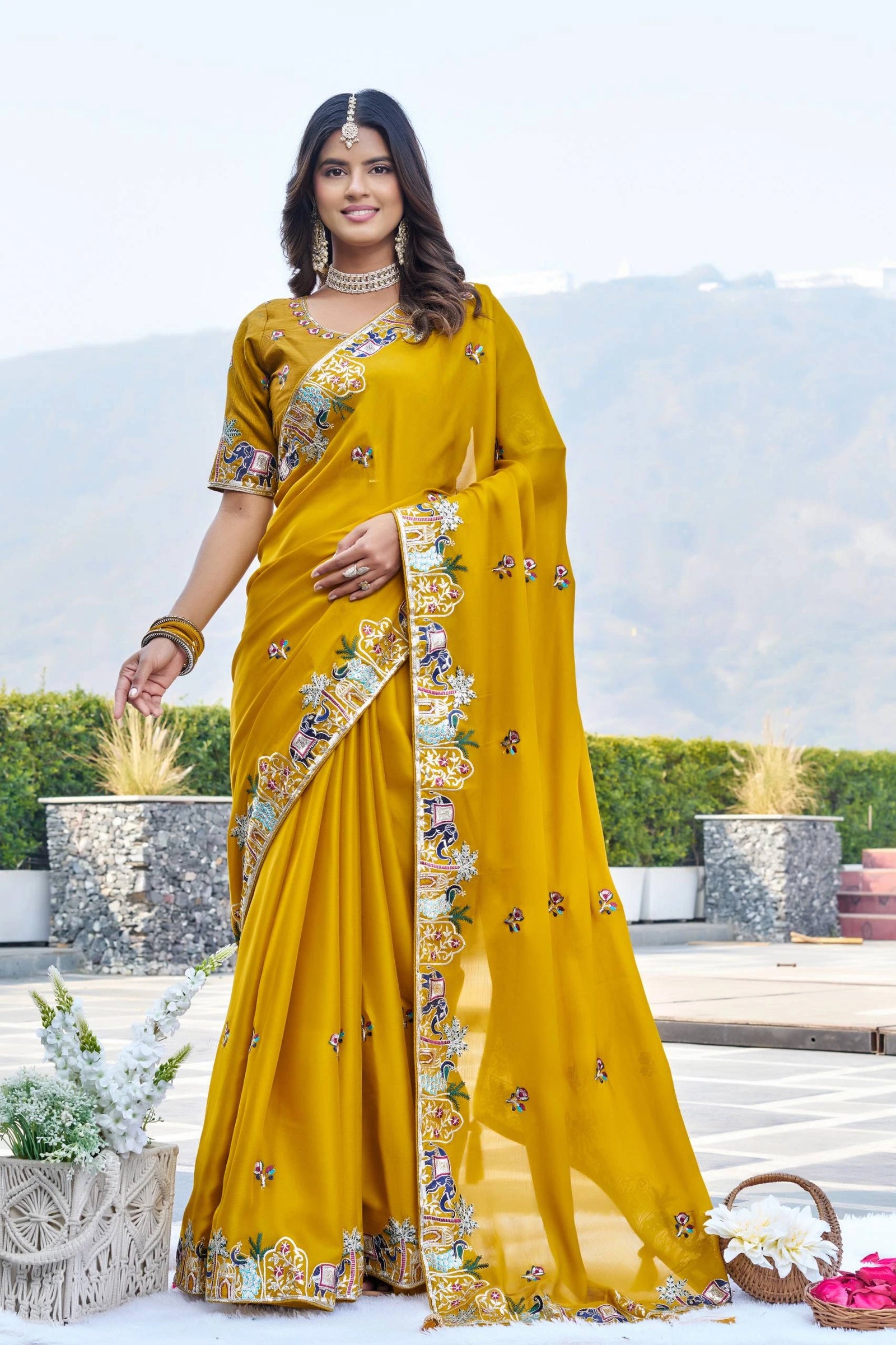 Woman wearing a yellow saree with floral patterns outdoors.