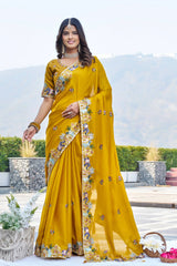 Woman wearing a yellow saree with floral patterns outdoors.
