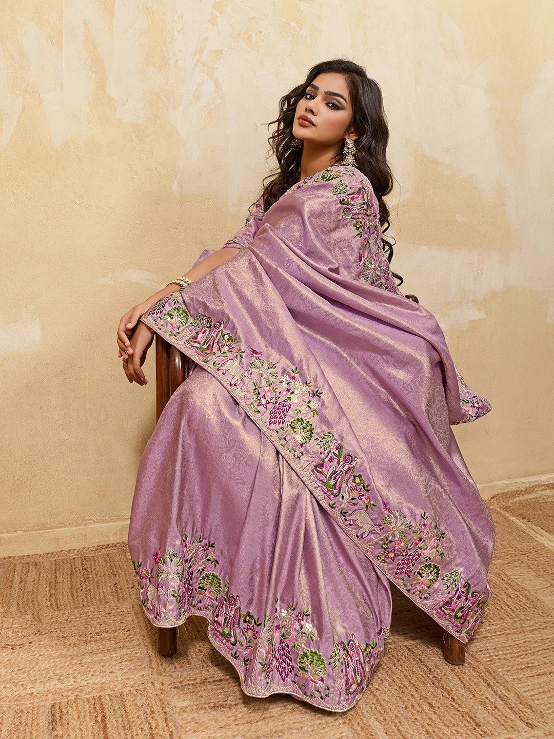 Woman wearing a lavender saree with floral embroidery against a beige background
