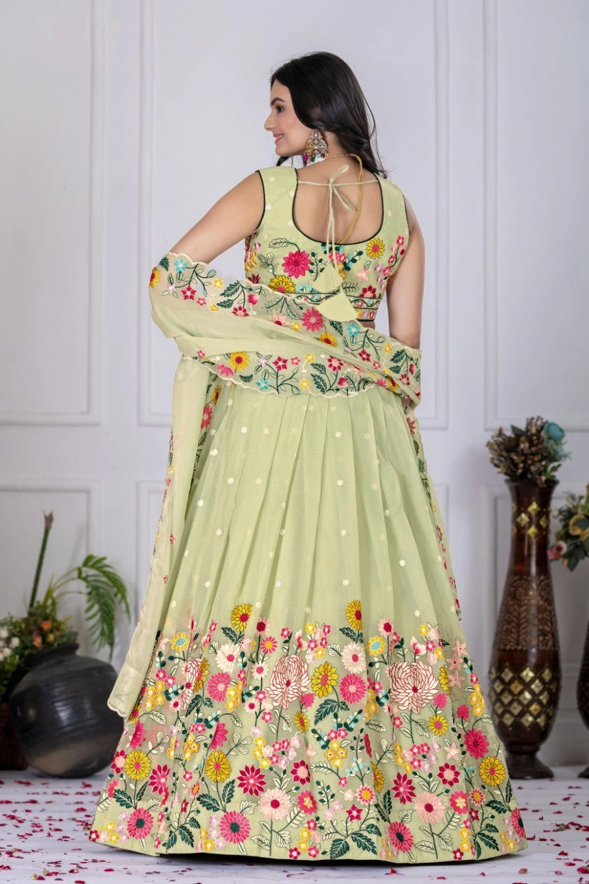 Woman wearing a light green floral embroidered dress in a decorated room.
