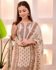 Woman wearing a traditional outfit with intricate patterns in a softly lit room.