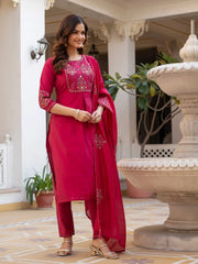 Woman in a pink traditional outfit standing in an elegant indoor setting.