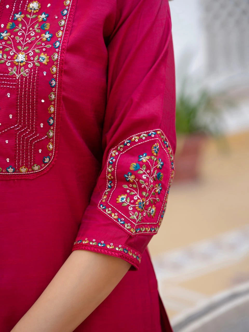 Close-up of a pink garment with intricate embroidery on a blurred background