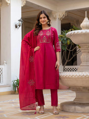 Woman in a red traditional outfit standing in an outdoor setting with decorative elements.