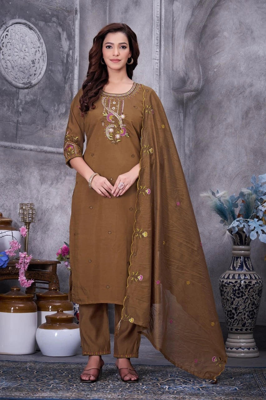 Woman wearing a brown traditional outfit with embroidery in a decorative setting.