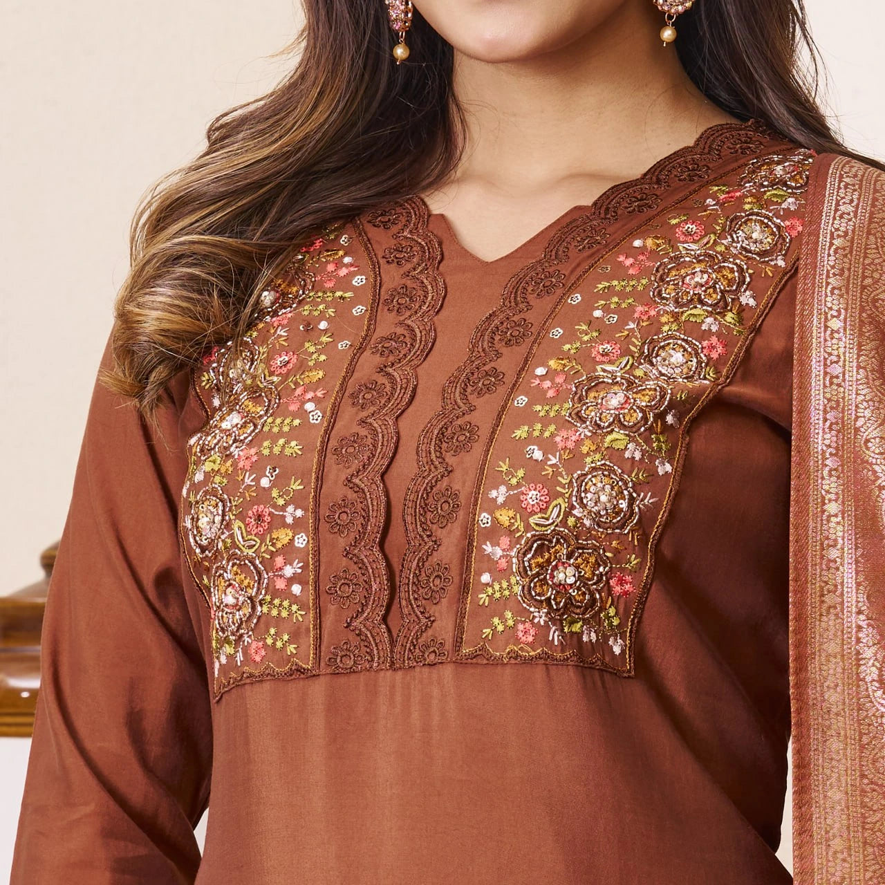 Brown embroidered traditional outfit with a plain background