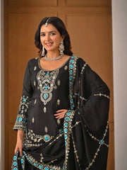 Woman wearing a black embroidered traditional outfit with turquoise stones against a wooden background