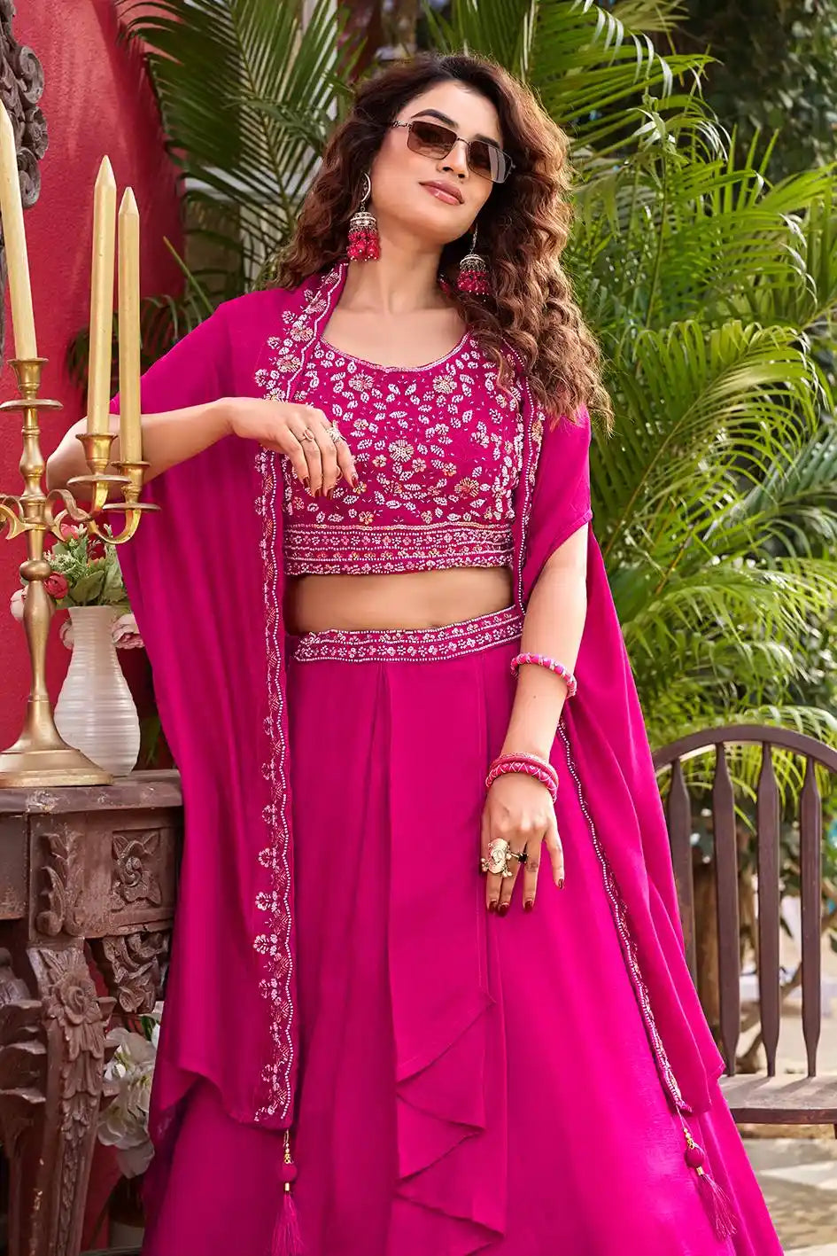 Woman in a bright pink traditional outfit with floral patterns, standing outdoors.