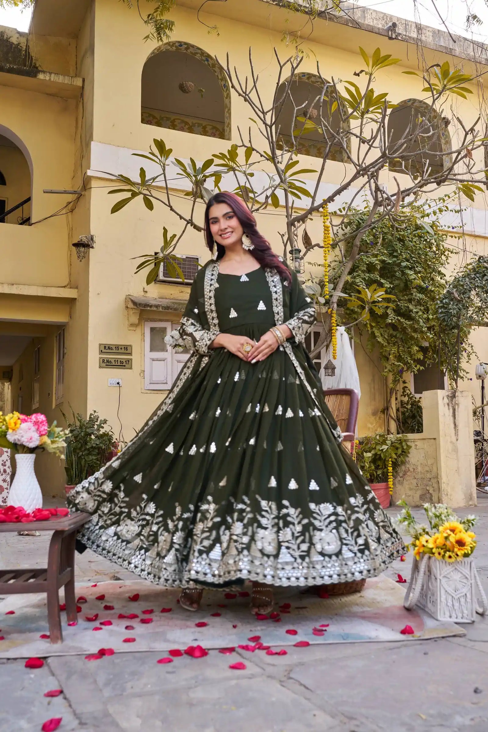 Woman in a green and white traditional outfit standing in front of a building with decorative elements.