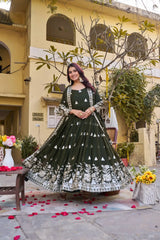 Woman in a green and white traditional outfit standing in front of a building with decorative elements.