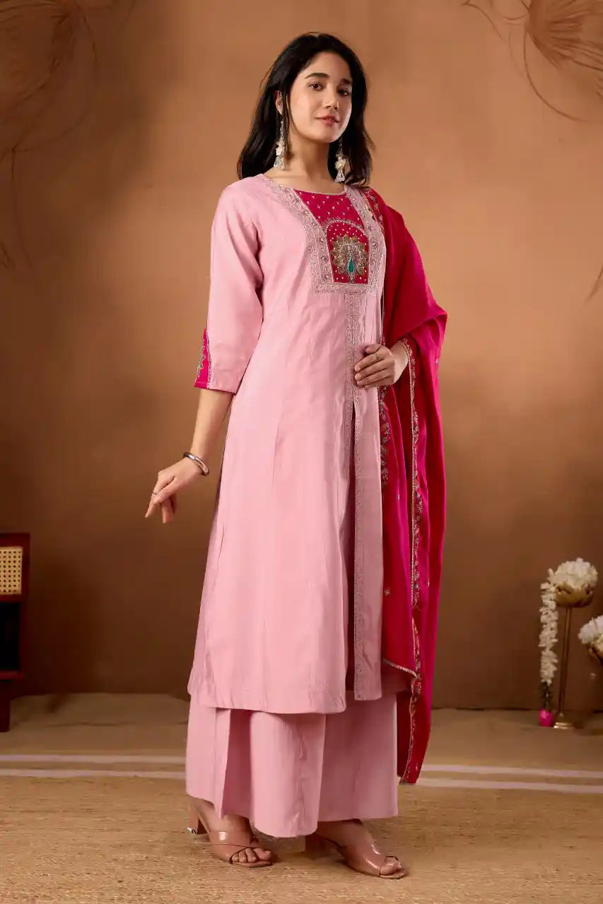 Woman wearing a pink traditional outfit with a red dupatta against a brown background