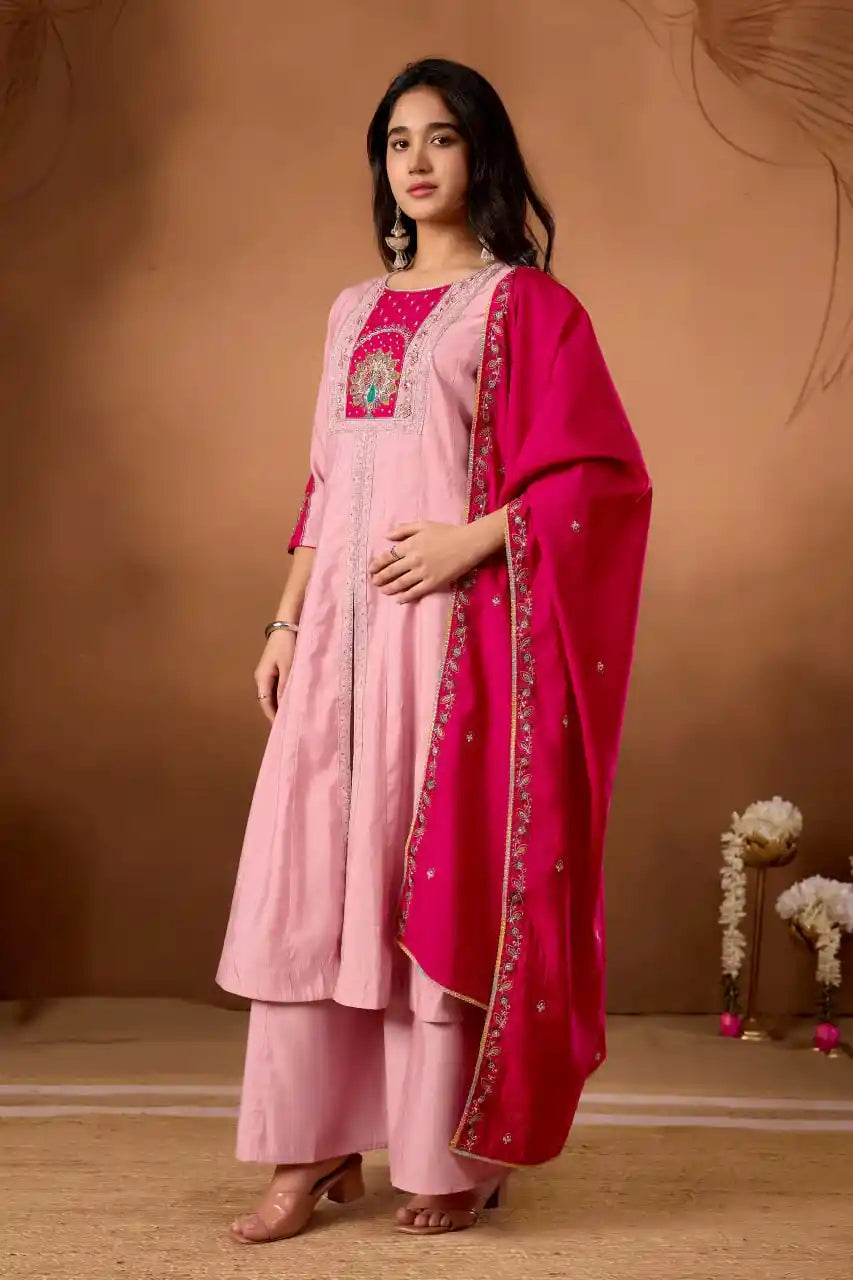 Woman wearing a pink traditional outfit with a red dupatta against a brown background