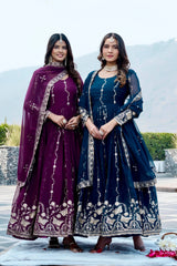 Two women in traditional embroidered dresses standing outdoors with mountains in the background.