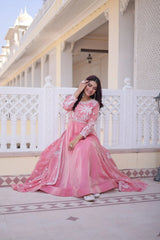 Woman in a pink traditional outfit standing on a balcony with white railings and architectural details.