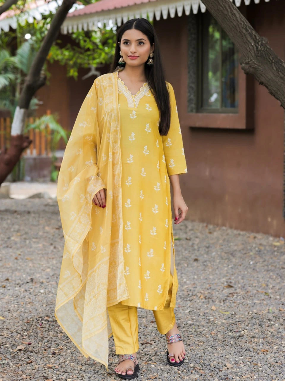 Woman wearing a yellow traditional outfit with a dupatta in an outdoor setting.