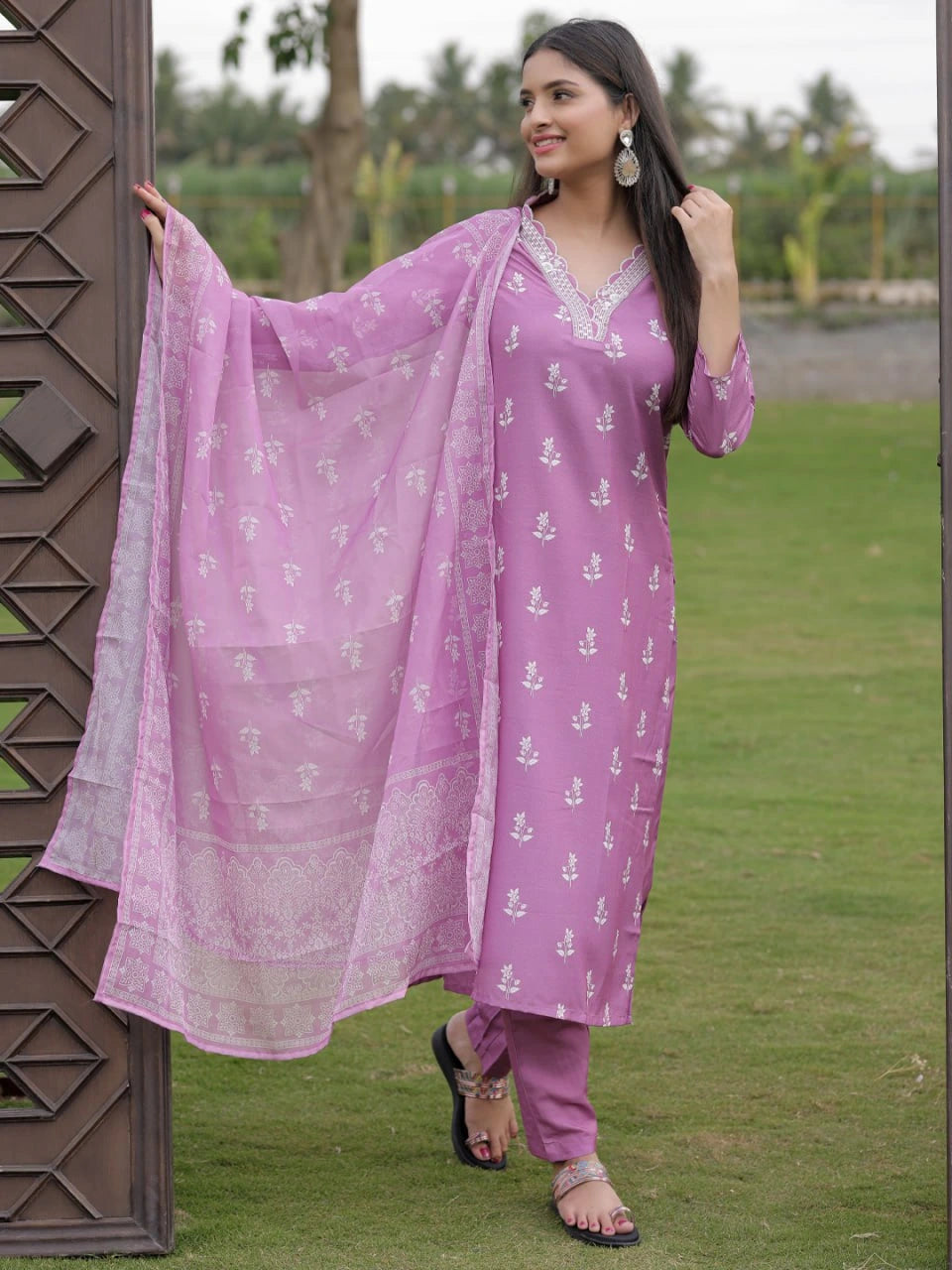 Woman in a purple traditional outfit with a matching dupatta standing outdoors.