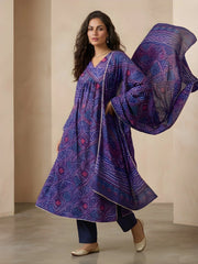 Woman wearing a purple patterned outfit with a matching dupatta against a beige background