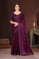 Woman wearing a purple saree with a matching blouse against a dark background