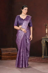 Woman wearing a purple saree with a matching blouse against a dark background
