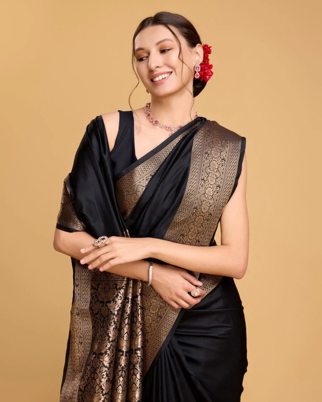Woman wearing a black and gold saree with a beige background