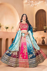 Woman in a traditional embroidered lehenga with a pink blouse in an elegant indoor setting.