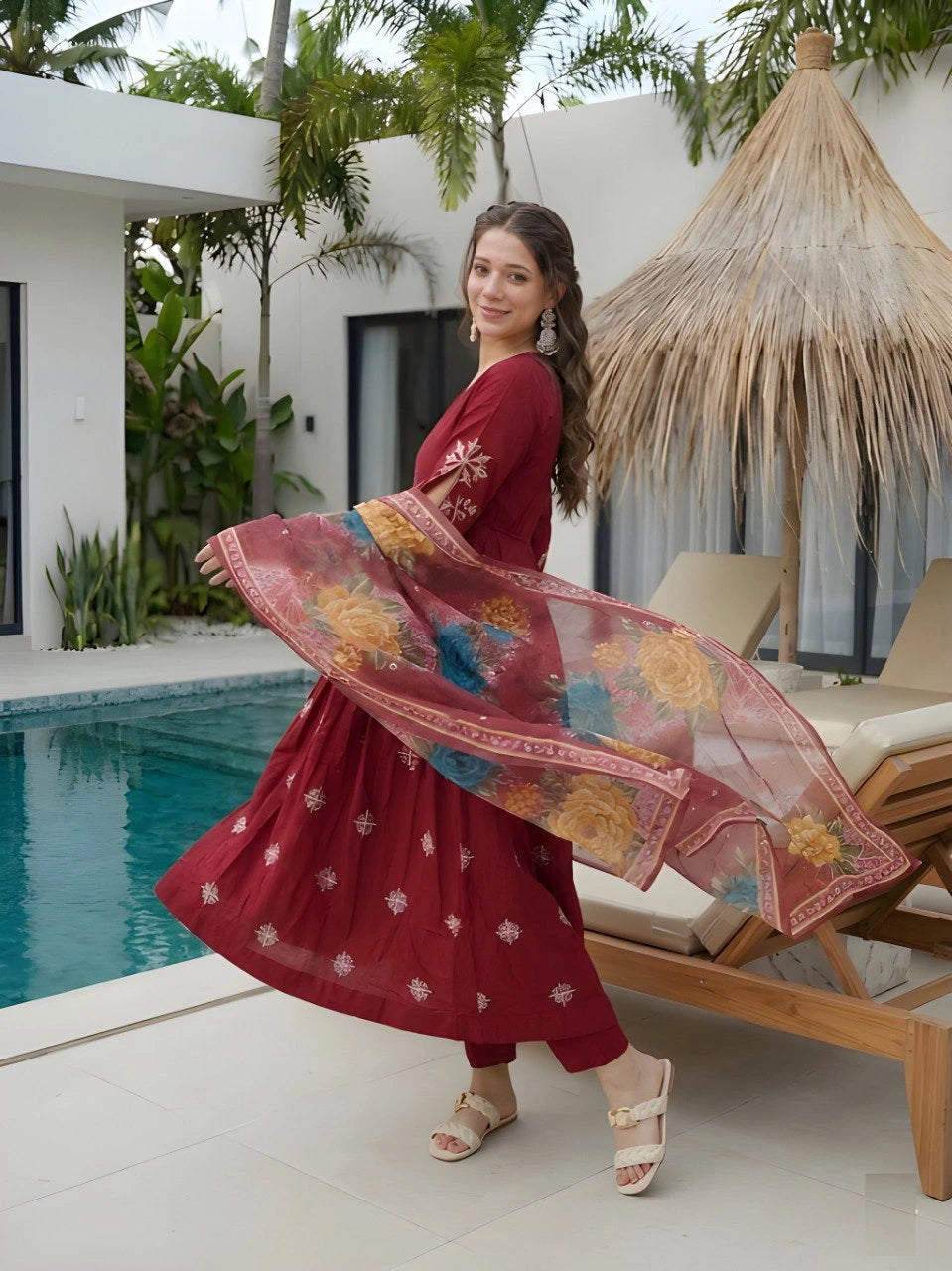 Woman in a red dress with floral patterns by a poolside