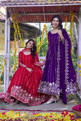 Two women in traditional red and purple dresses sitting on a swing decorated with flowers.