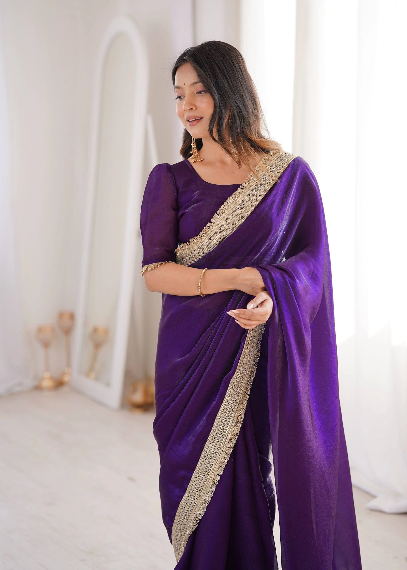 Woman wearing a purple saree with gold border indoors