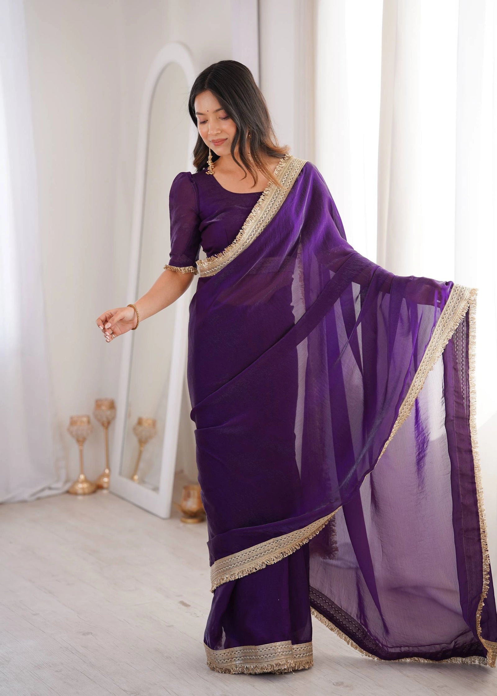 Woman wearing a purple saree with gold border in a minimalistic setting