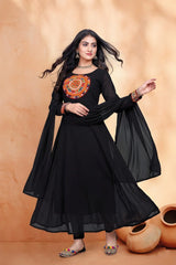 Woman wearing a black traditional outfit with colorful embroidery against an orange background