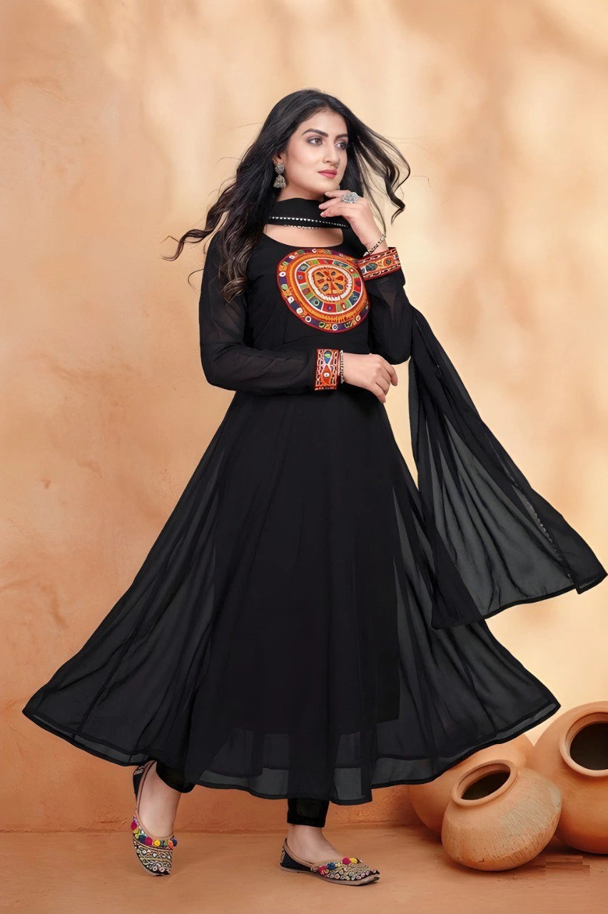 Woman wearing a black dress with orange embroidery against a beige background