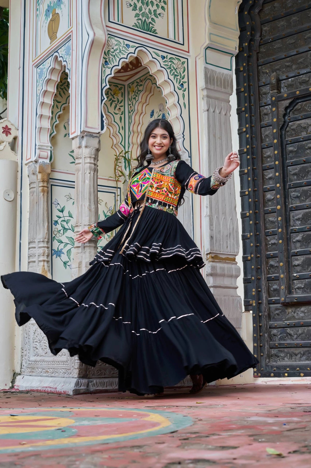Woman in traditional outfit standing in front of an ornate architectural background