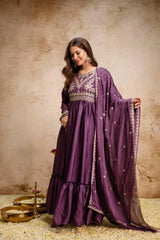 Woman wearing a purple traditional outfit with intricate designs on a textured beige background