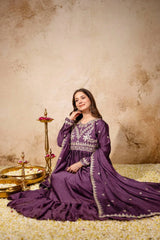 Woman in a purple traditional outfit sitting on a textured floor with decorative elements.
