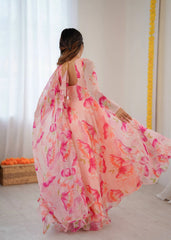Woman wearing a pink floral dress in a room with white curtains and a yellow decorative item.